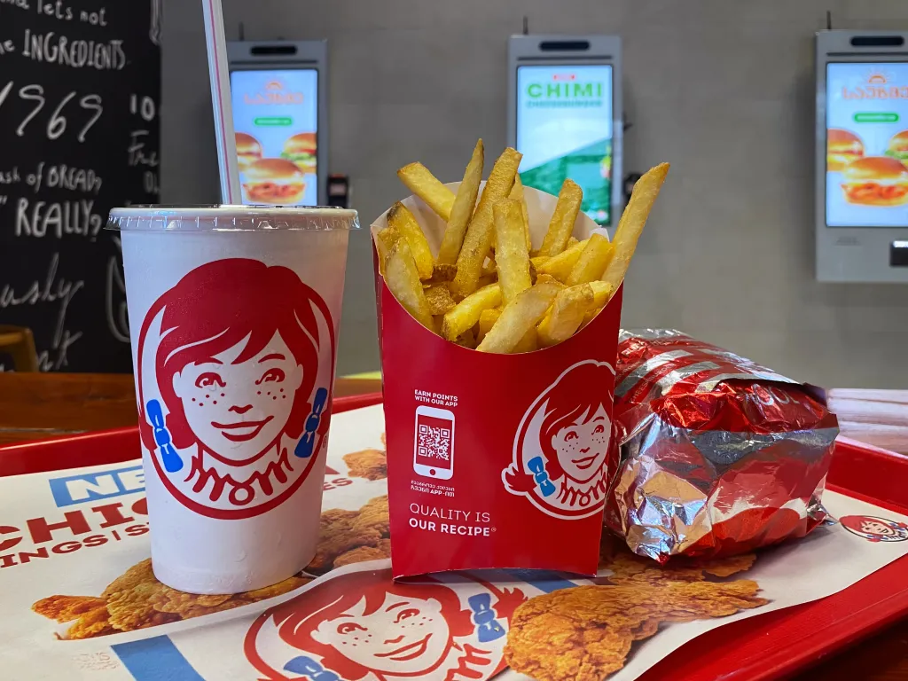 A Wendy's combo meal on a red tray with a drink, fries, and a foil-wrapped burger.