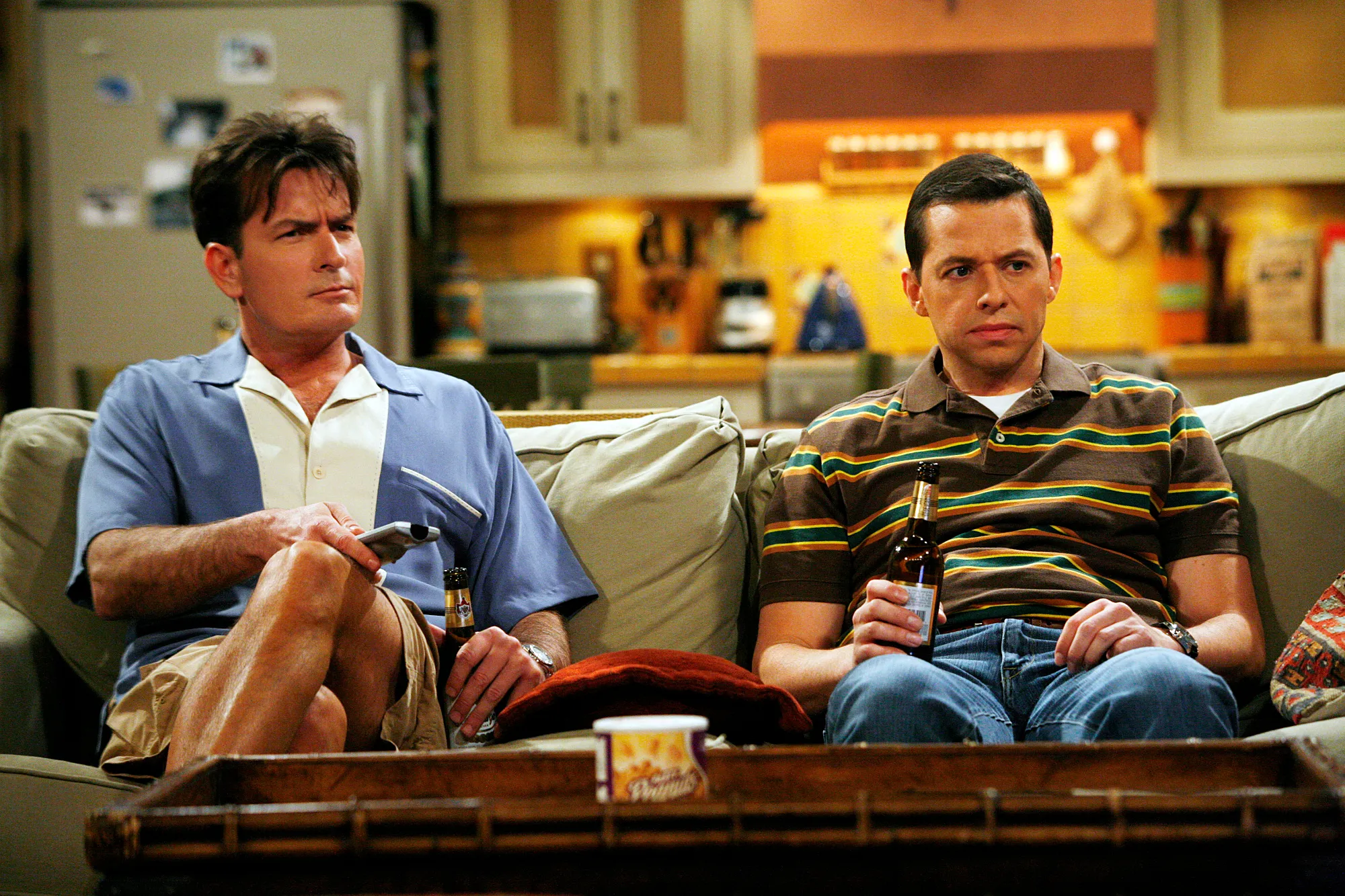 Charlie Sheen (left) and Jon Cryer (right) sit on a couch in a scene from 