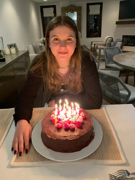 Coco Arnold with a chocolate birthday cake topped with raspberries and lit candles.