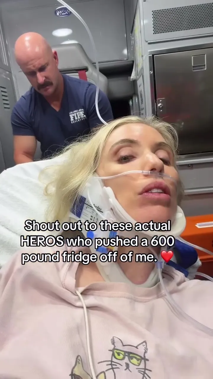 Comedian Laura Clery in an ambulance after being crushed by a 600-pound fridge, with a Los Angeles Fire Department medical professional behind her.