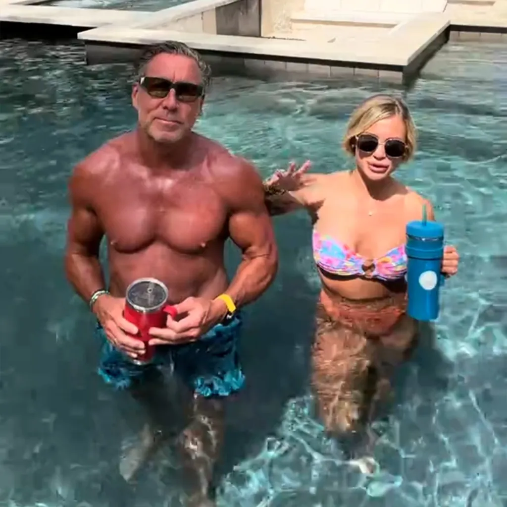 A man and a woman, a couple with a 34-year age gap, standing in a pool with drinks.