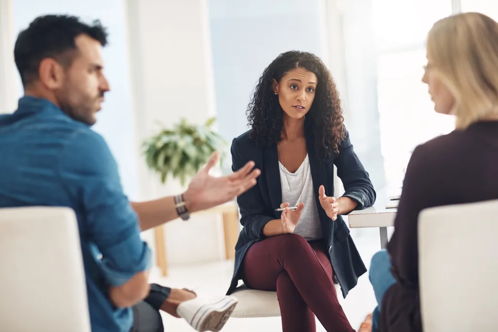 A female therapist mediating a discussion between a male and female couple.