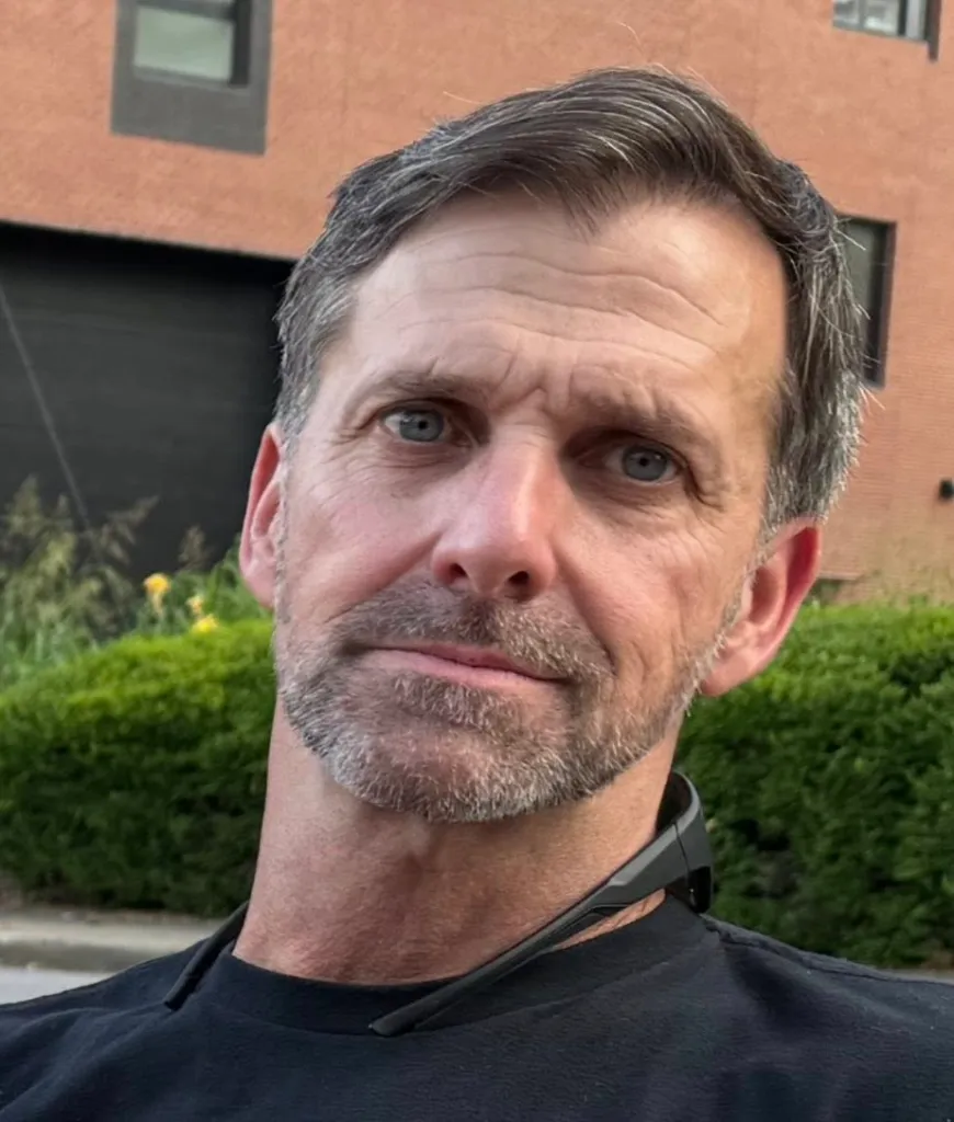 Craig Berry, a white man with graying hair and beard, wearing a black shirt, with sunglasses resting on his neck.