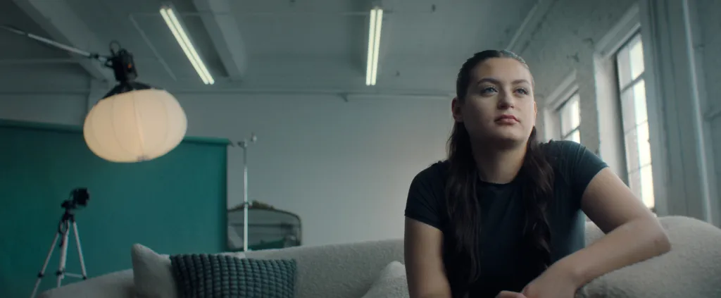Rosie Graham looking off to the right, sitting on a couch.