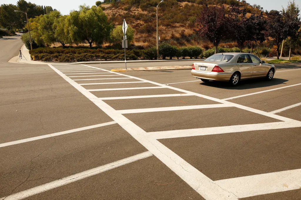 A gold sedan parked near a crosswalk on Triunfo Canyon Road and Saddle Mountain Drive.