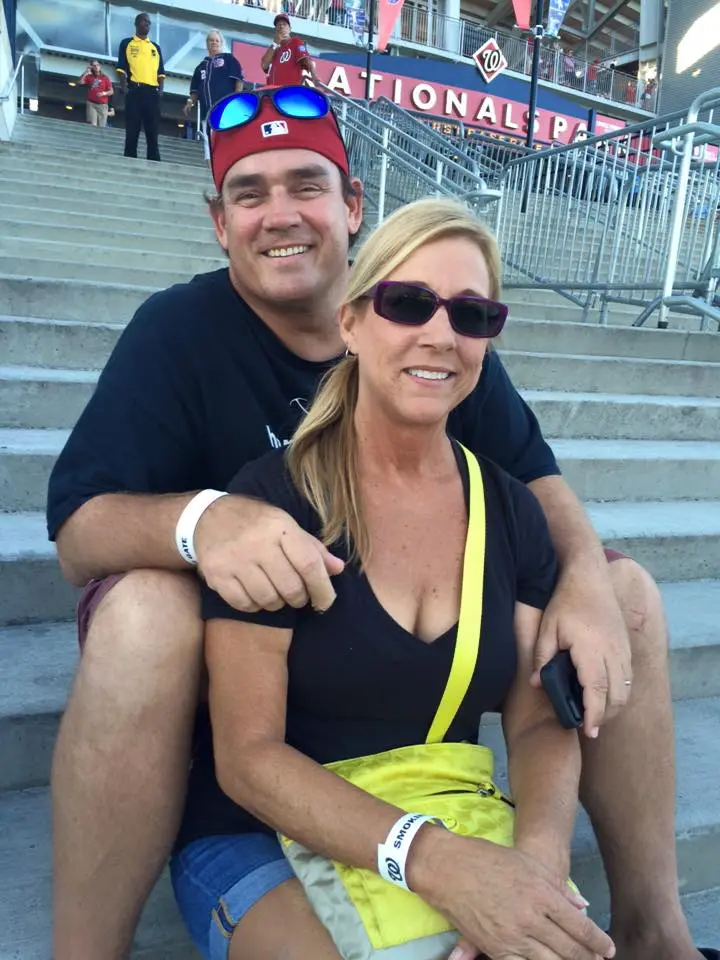 A man and a woman smile for a photo while sitting on stadium stairs.