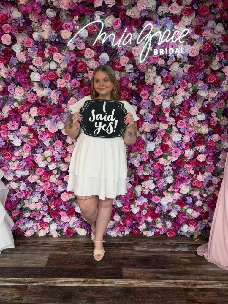 A young woman in a white dress holds a 