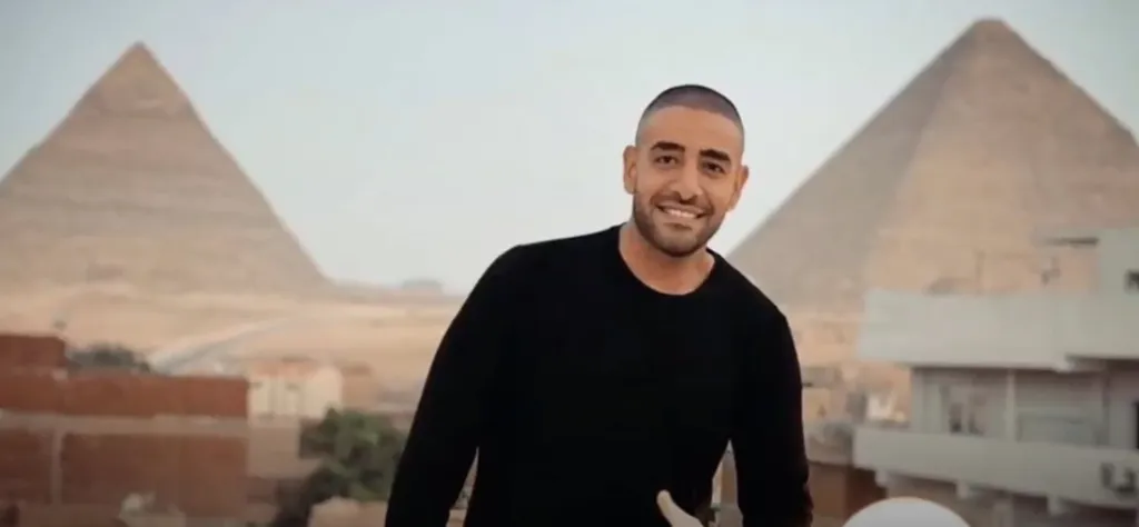 A man in a black shirt smiling with the Giza pyramids in the background.