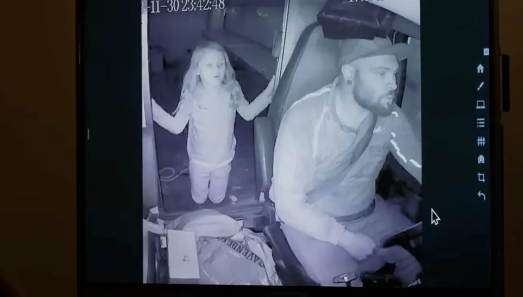 Image from inside Tanner Horner's FedEx truck showing Athena Strand standing in the truck's doorway and Horner in the driver's seat.