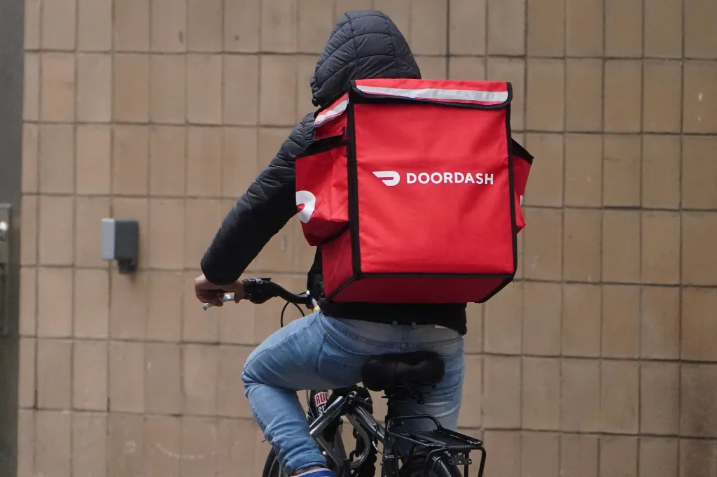 A DoorDash delivery person on a bicycle.