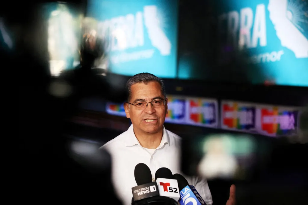 Xavier Becerra campaigning in West Hollywood with several microphones in front of him.