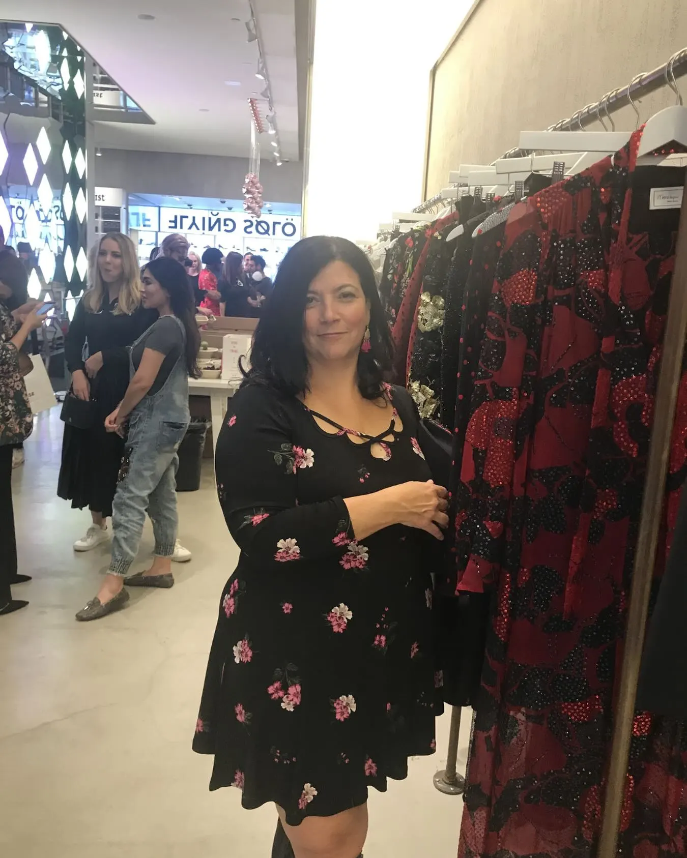 Denise Cesare, a small business owner, posing next to a rack of clothing.