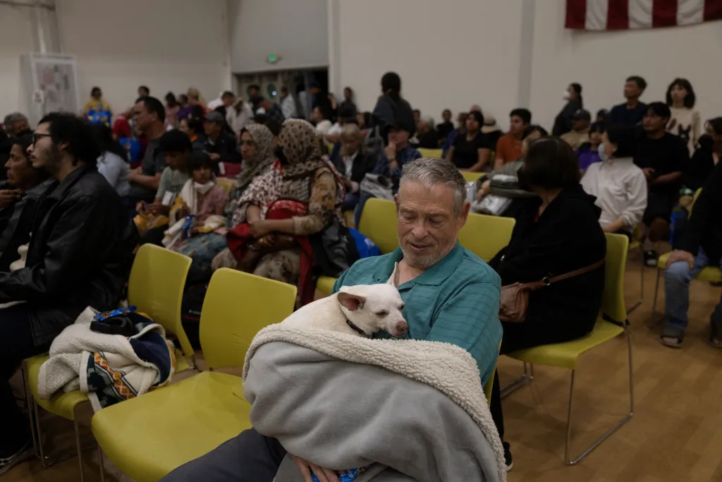 Dennis Christian holding his dog Rue at a temporary shelter after being evacuated due to a chemical tank failure.