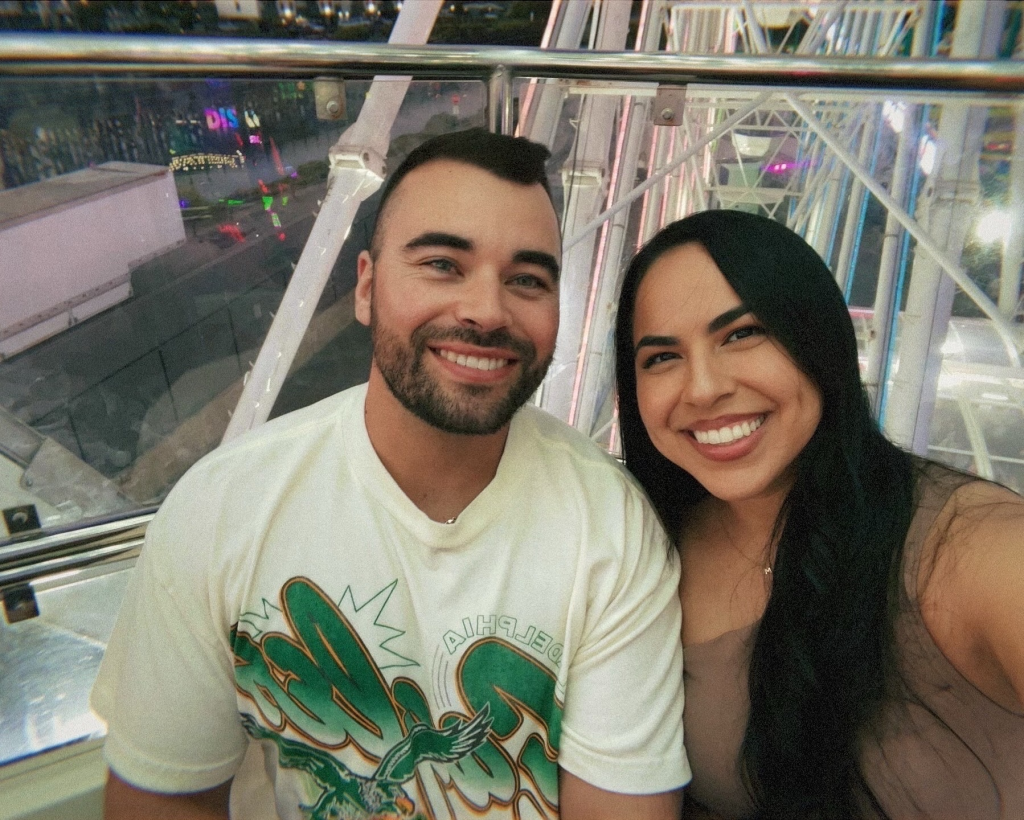 Desiree Paula Noelle and Max Austin Mooney smiling in a Ferris wheel car.
