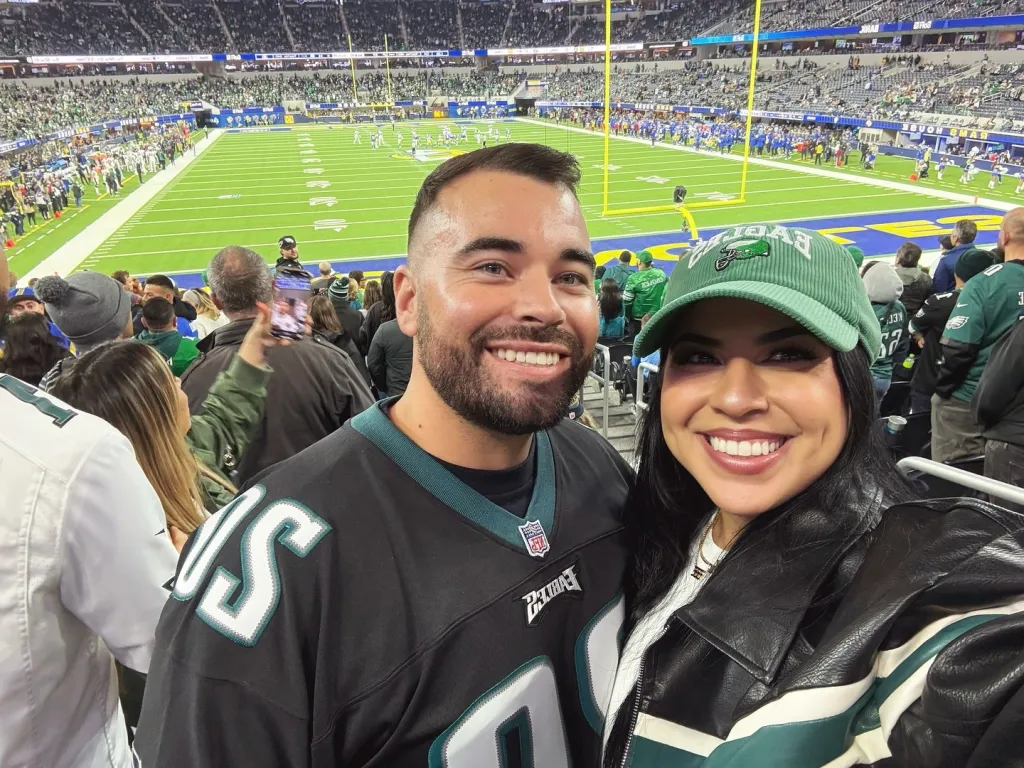 Desiree Paula Noelle and Max Austin Mooney smiling at an American football game.