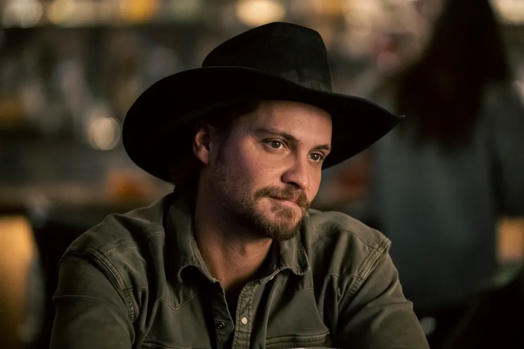 Luke Grimes as Kayce Dutton wearing a cowboy hat and a green shirt.