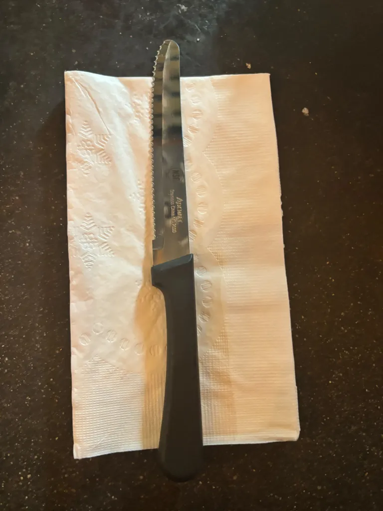 A serrated knife on a white paper napkin.