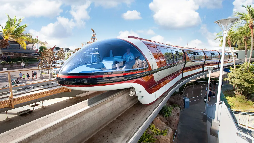 Red and white Disneyland Monorail traveling on a single rail through the resort.