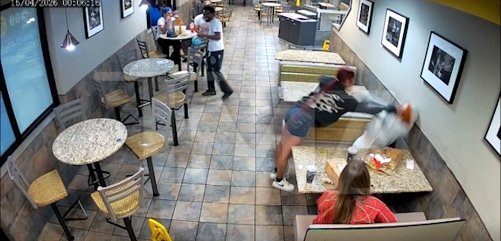 Video still of a woman in a black shirt hitting a person in a white hoodie inside a McDonald's.