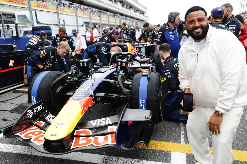 DJ Khaled smiles on the grid with Max Verstappen's Oracle Red Bull Racing car and crew.