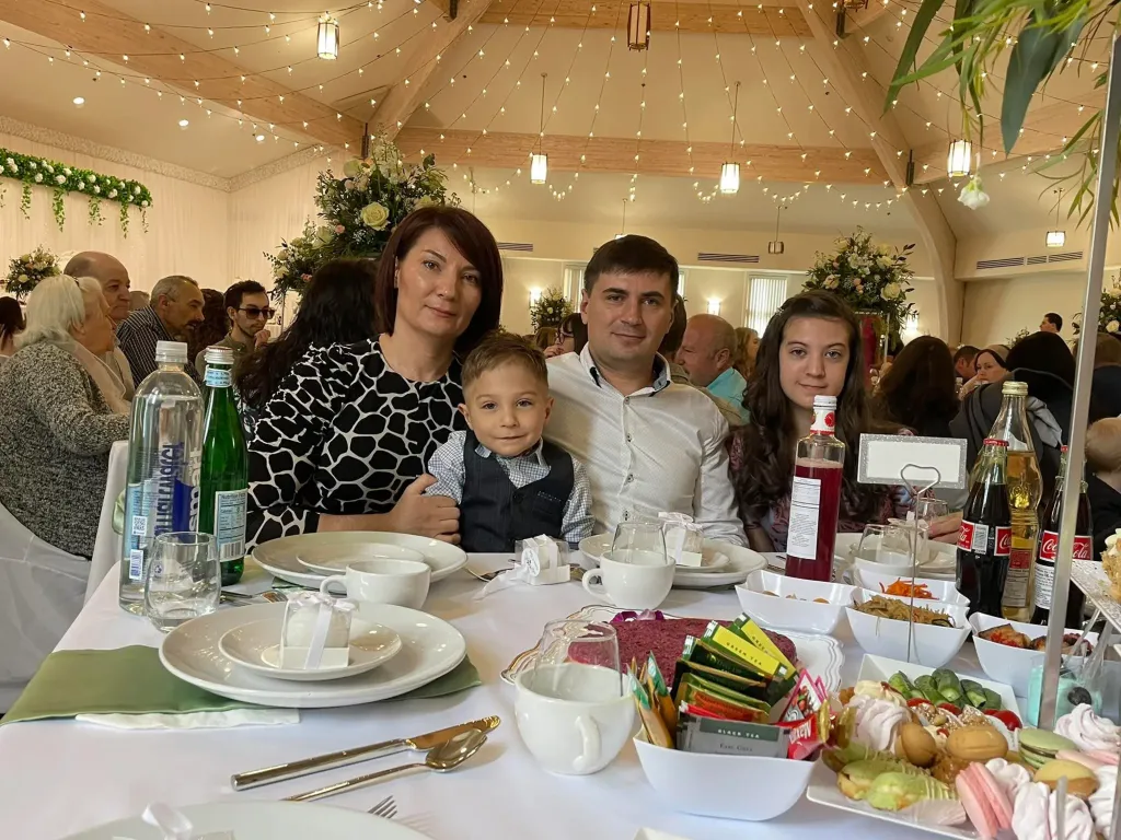 The Doncev family, Dmitri, Ecaterina, Emily, and Mark, seated at a table at a party.