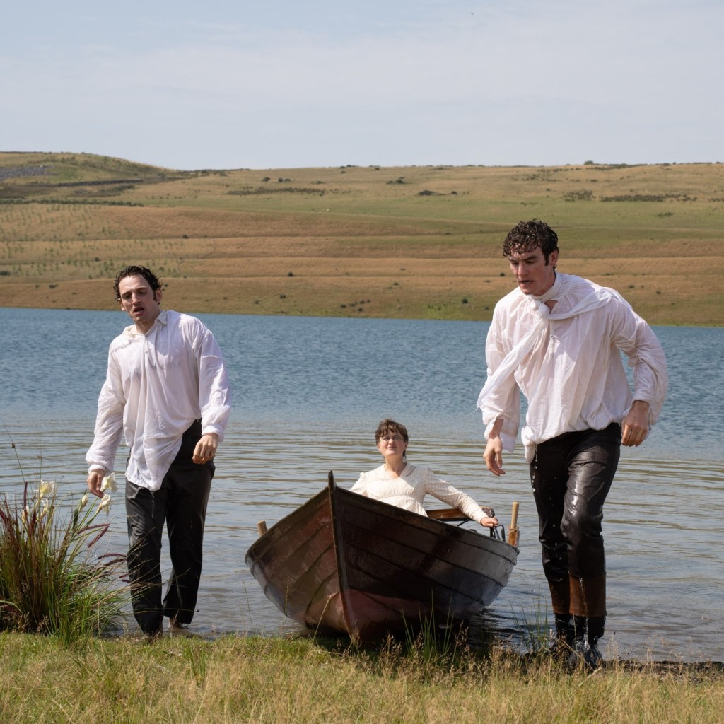 Donal Finn and Laurie Davidson, wet from the lake, pull a boat with Ella Bruccoleri ashore.