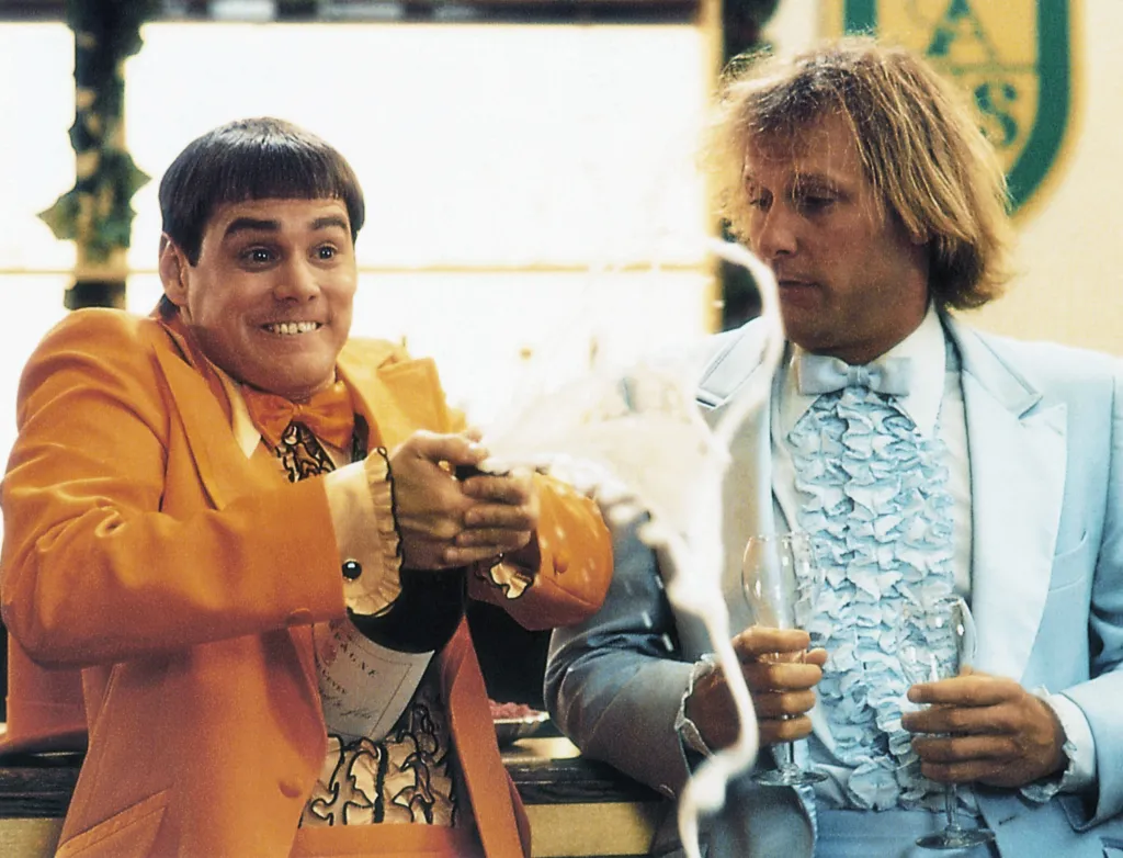 Jim Carrey pops a champagne bottle as Jeff Daniels looks on in 
