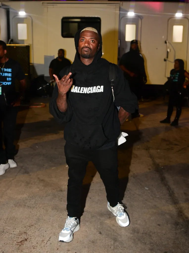 Ray J in a black Balenciaga hoodie, black pants, and gray sneakers, giving a peace sign.