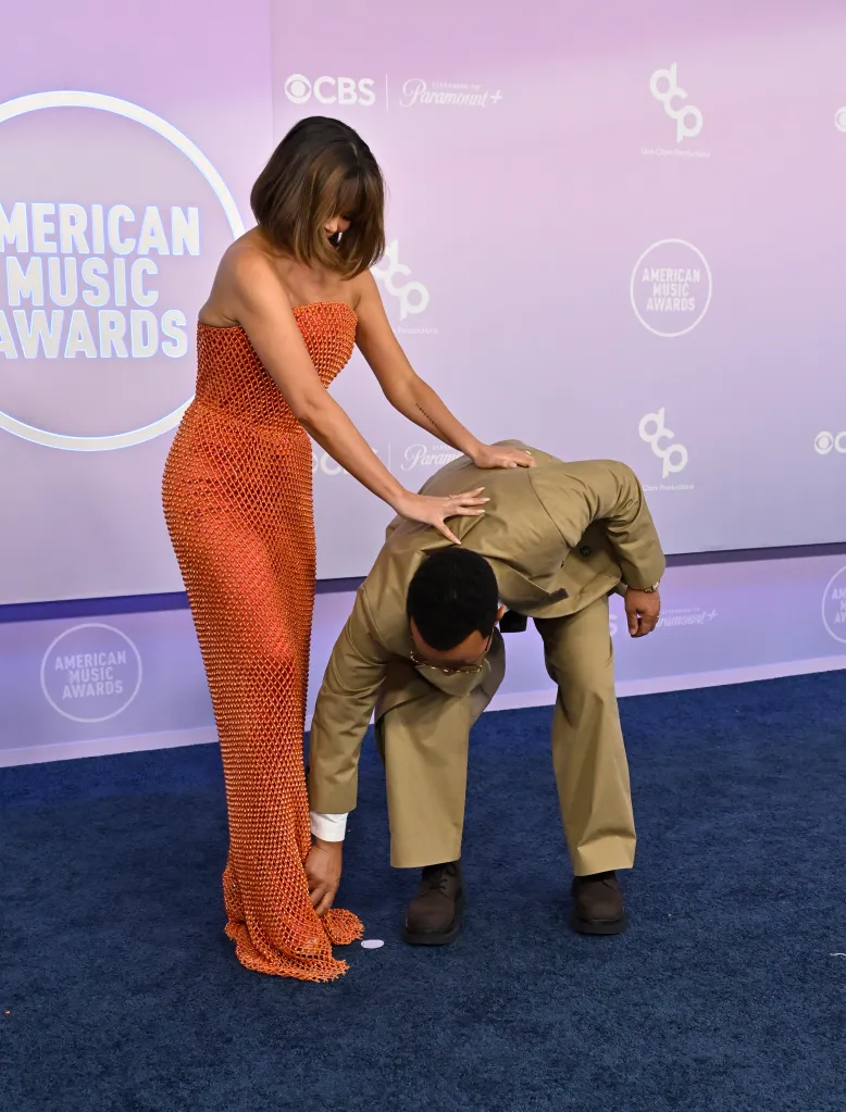 Chrissy Teigen in an orange dress and John Legend in a tan suit at the American Music Awards.