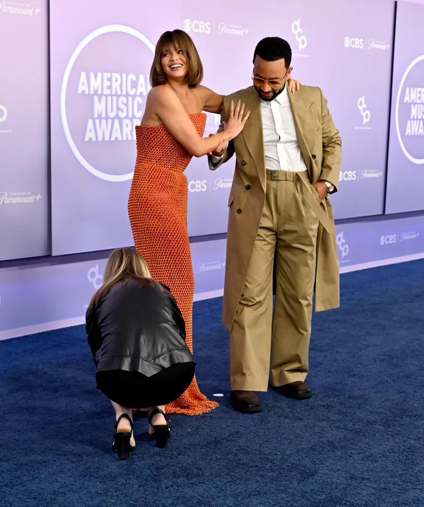 Chrissy Teigen in an orange dress and John Legend in a tan suit at the American Music Awards.