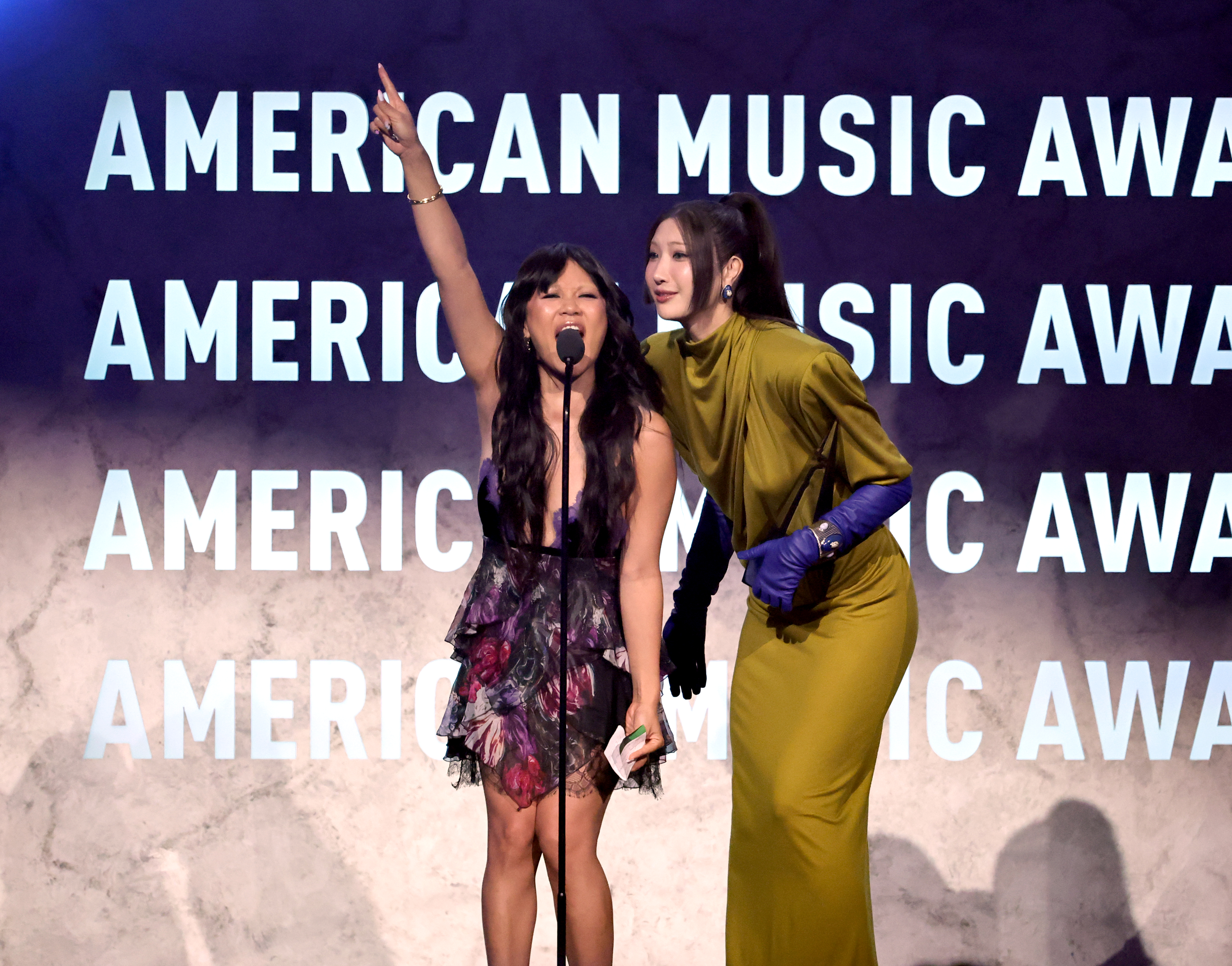 Rei Ami and EJAE speaking onstage at the 52nd American Music Awards.