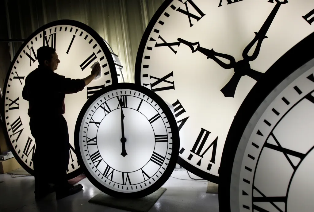 A man cleaning the face of a large clock.