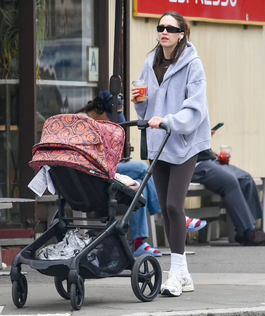 Elise Hewitt pushing a baby pram while holding a coffee.