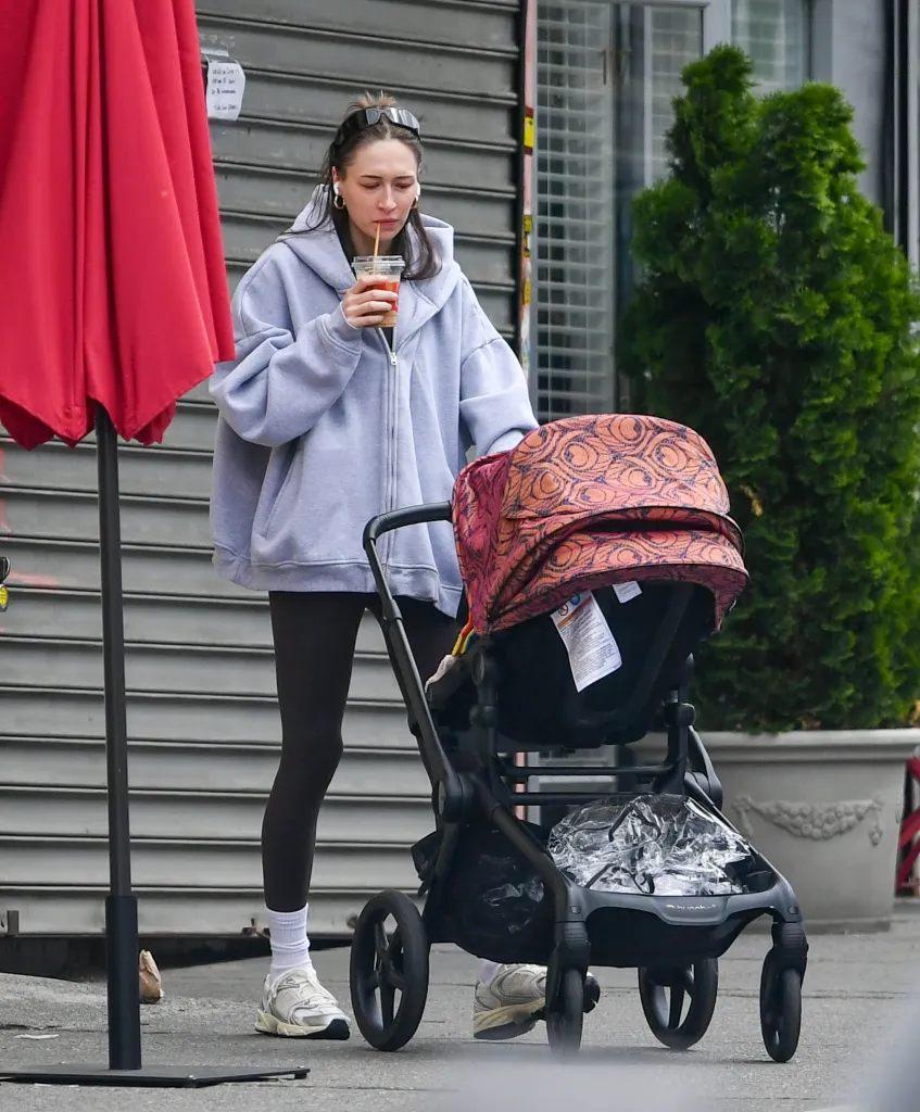 Elise Hewitt pushes a stroller while drinking a beverage.