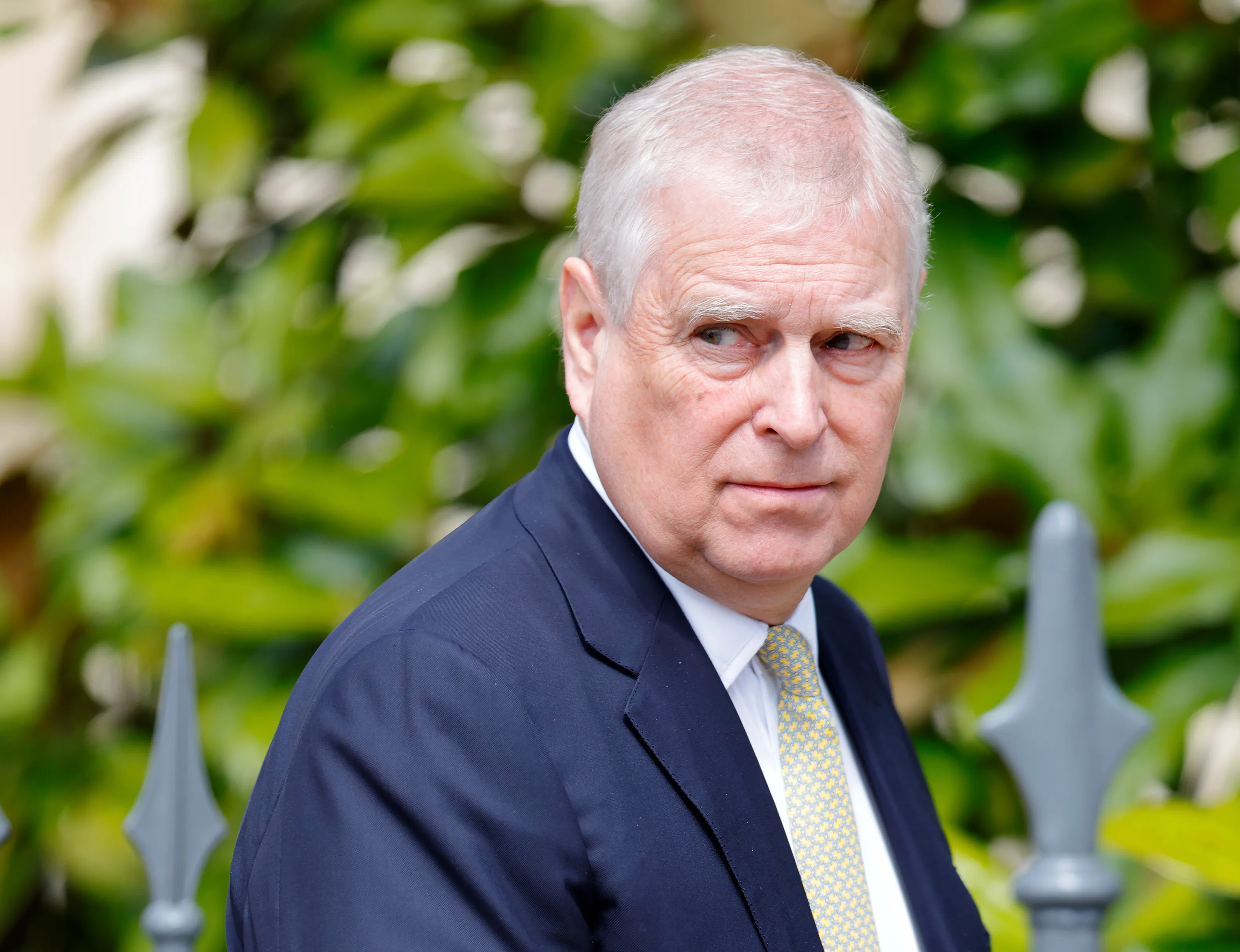 Prince Andrew, Duke of York, in a suit and tie, looks away from the camera.