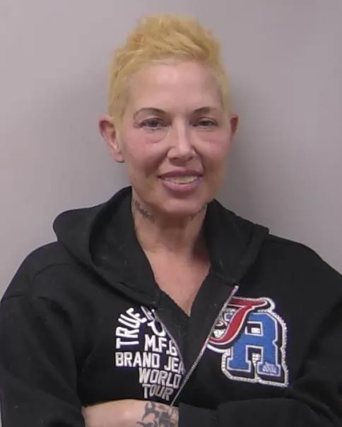 Mugshot of Kim Scott smiling with short blonde hair and a black hoodie.