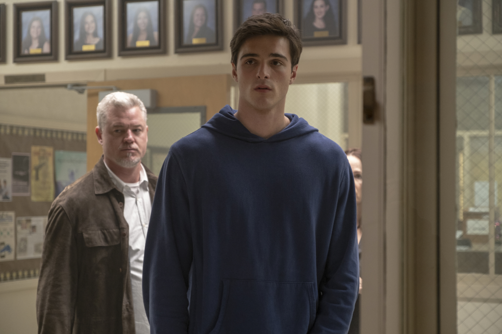 Actor Jacob Elordi as Nate Jacobs in a blue hoodie, with Eric Dane as Cal Jacobs in a brown jacket behind him.
