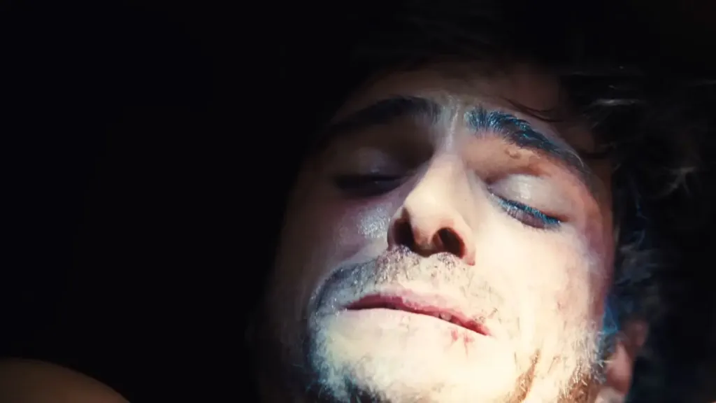 Jacob Elordi with closed eyes and blue glitter on his eyelids.