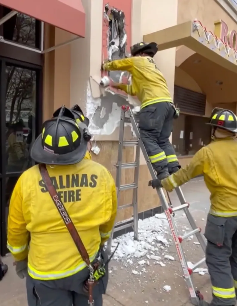 Salinas firefighters breaking into a wall to rescue a person.