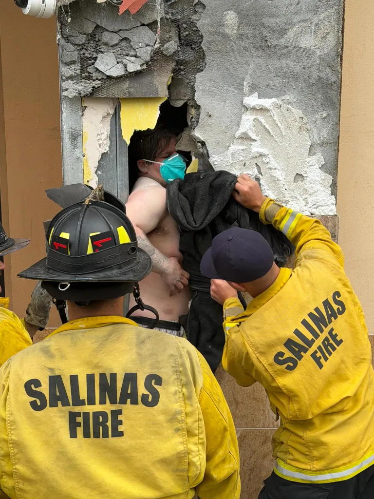 Firefighters helping a man trapped inside a wall.