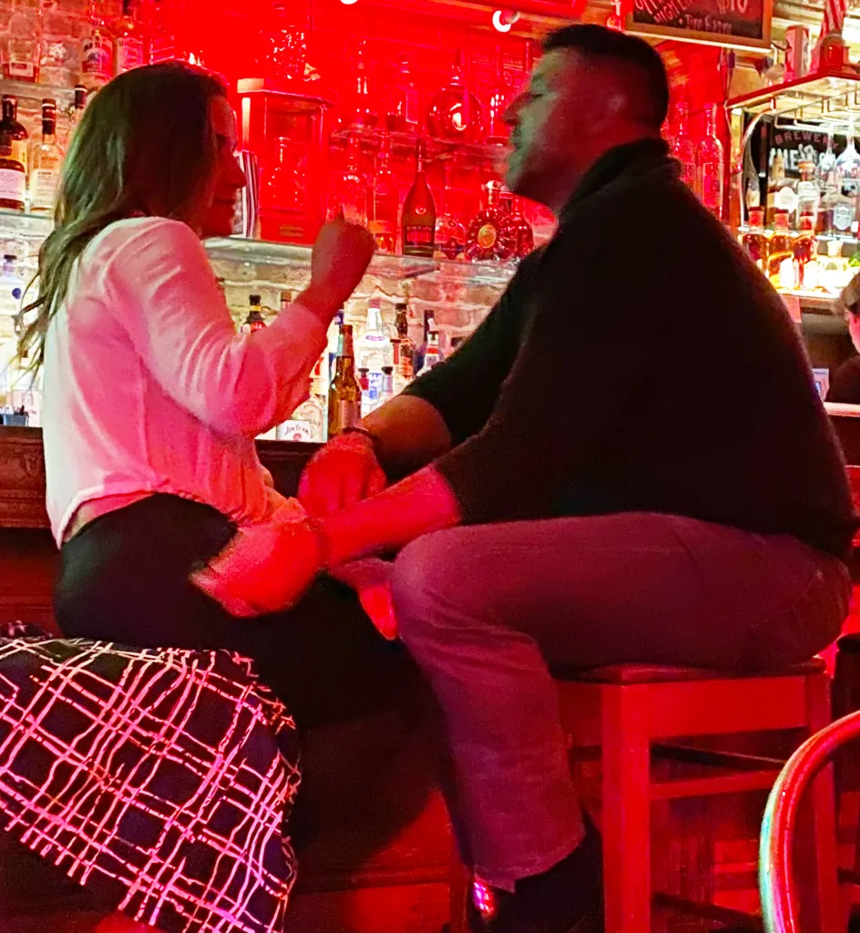 Mike Vrabel and Dianna Russini holding hands at a bar.