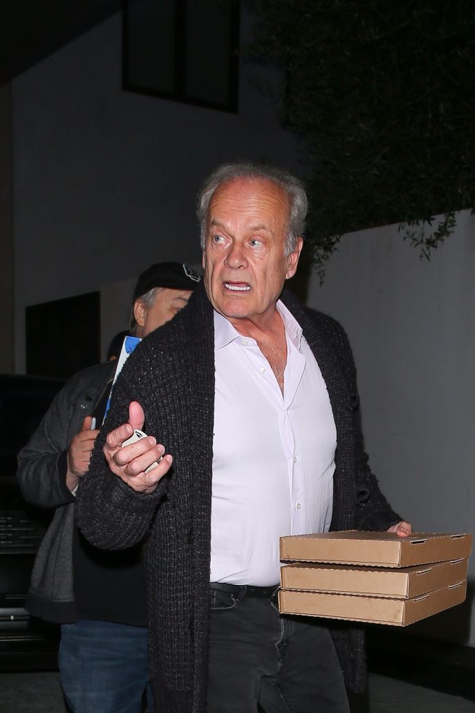 Kelsey Grammer holding a stack of three pizza boxes.