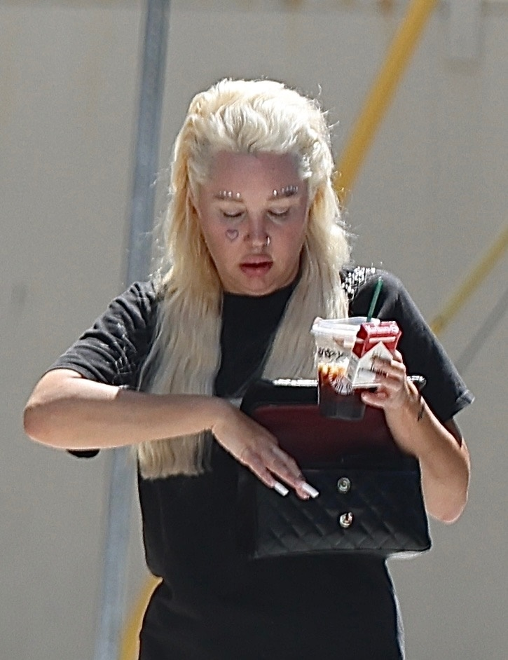 Amanda Bynes with platinum-blonde hair and jeweled eyebrows, holding a coffee and pack of Marlboro cigarettes.