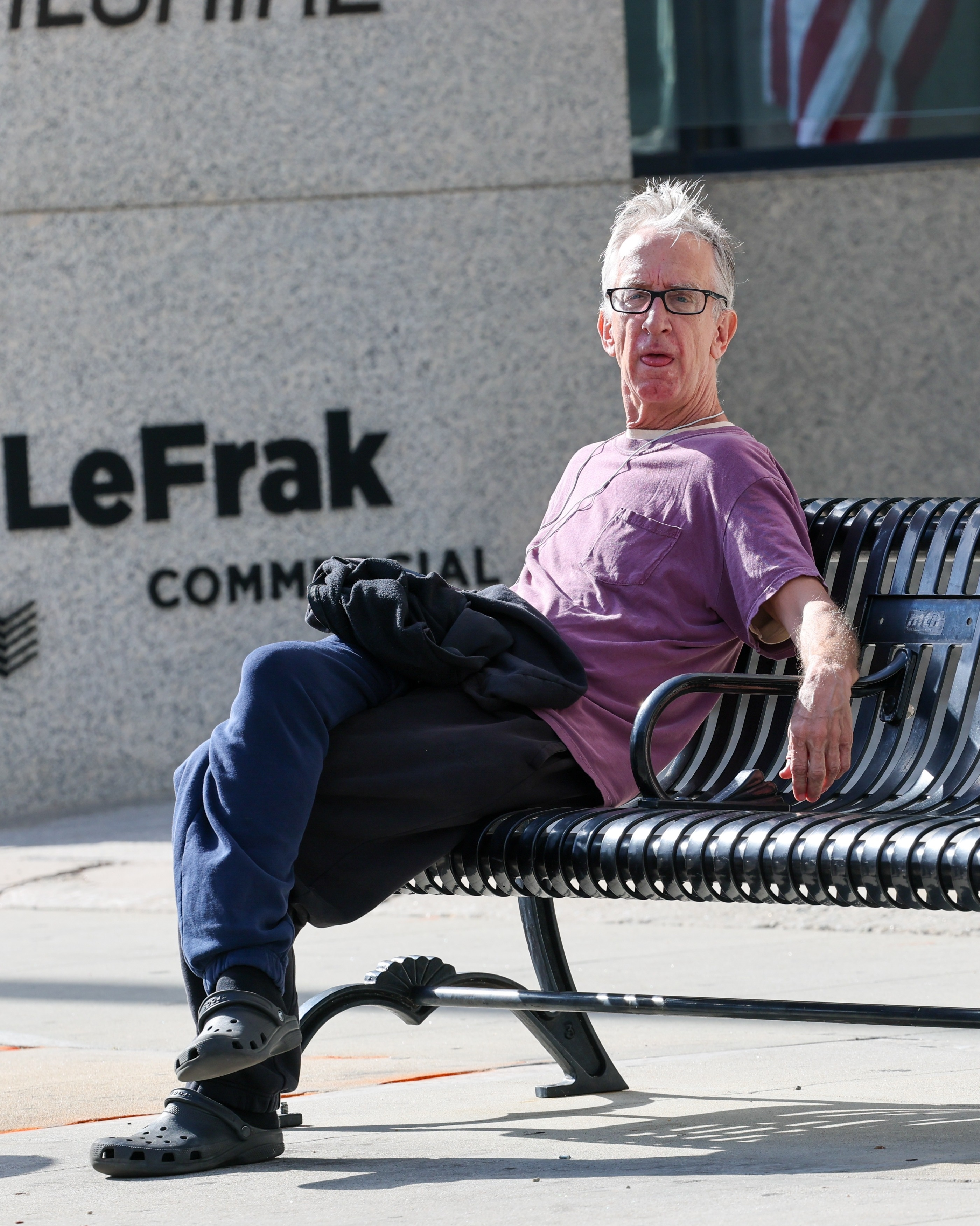 Andy Dick sitting on a bus stop bench in Los Angeles.