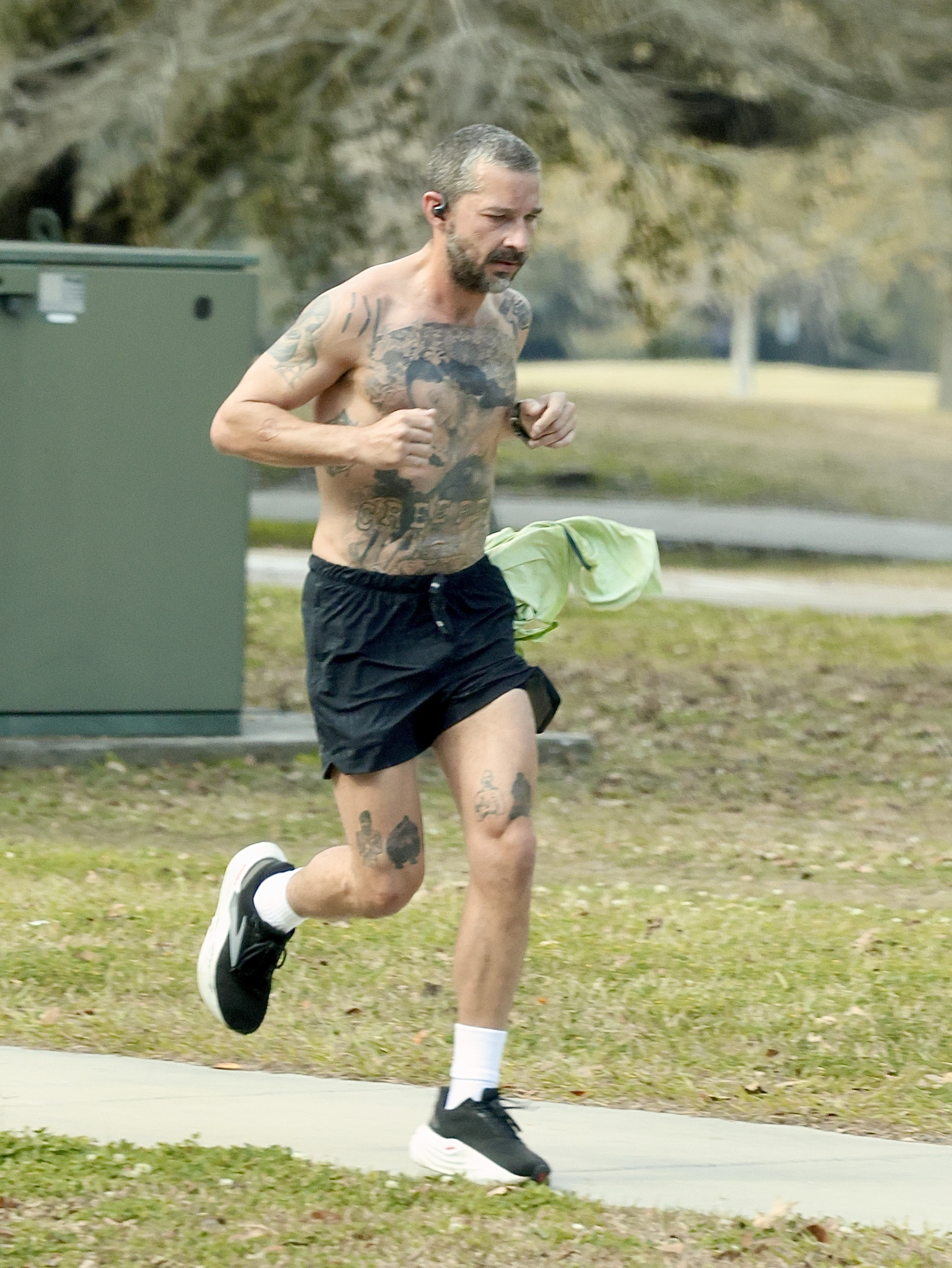 Shia LaBeouf jogging shirtless with visible tattoos.