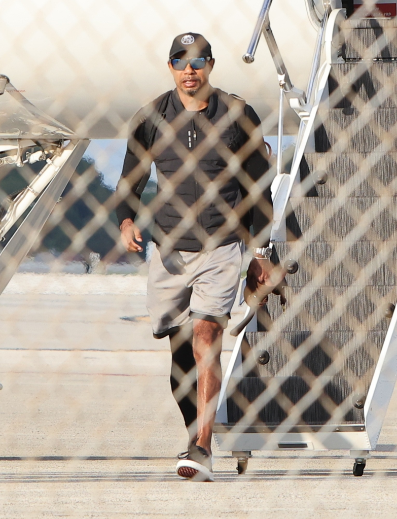 Tiger Woods disembarking a private jet, carrying a dog.