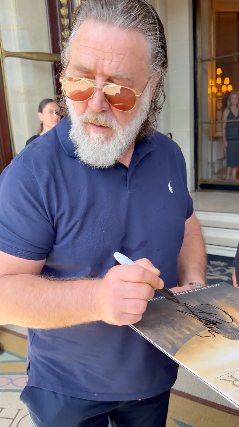 Russell Crowe signing autographs for fans outside a hotel in Paris.