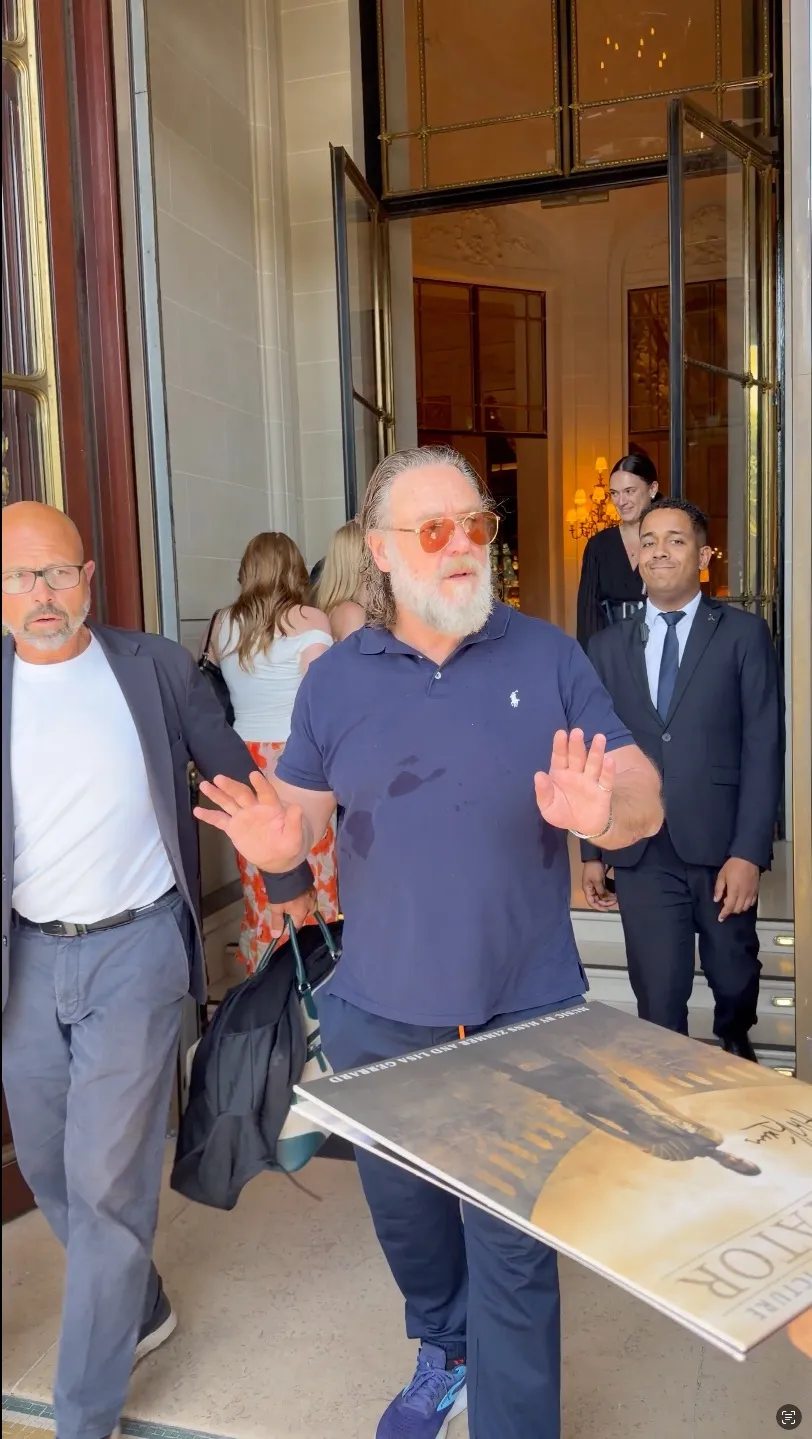 Russell Crowe holding up his hands, preventing fans from approaching him for autographs.