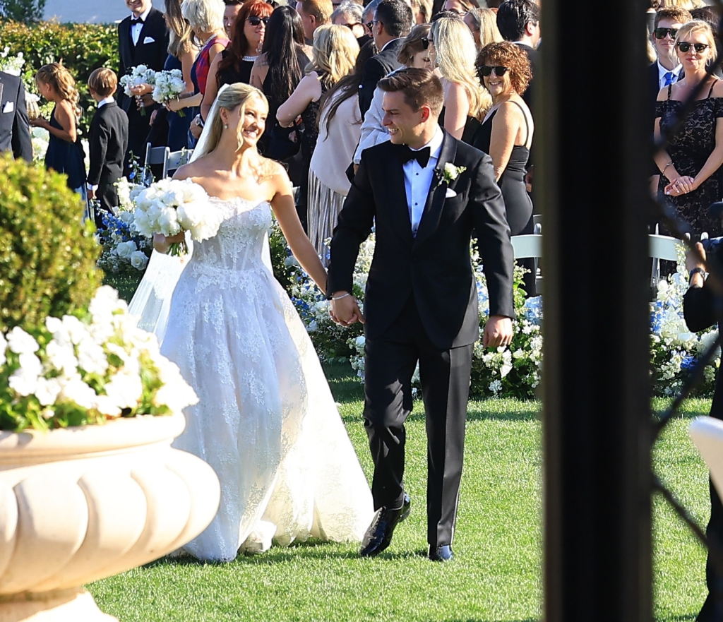 Ava Locklear and Tyler Farrar holding hands while walking down the aisle at their wedding.