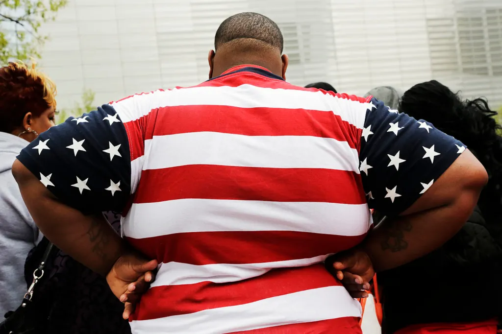 The back of an overweight person wearing a red, white, and blue American flag shirt.